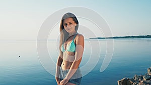 Happy young woman at beach. Girl tourist is wearing bikini on vacation gesturing peace sign at camera