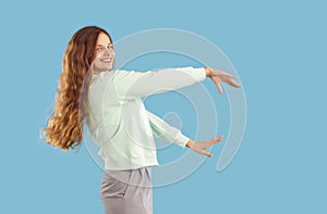 Happy young woman with beautiful long blond hair dancing isolated on blue background