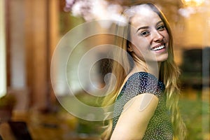 Happy young woman behind a window glass