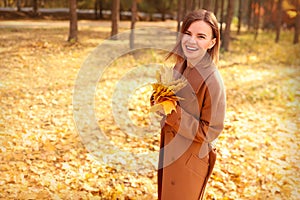 Happy young woman in a beige coast walks outdoors in autumn park, concept autumn.