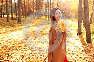 Happy young woman in a beige coast walks outdoors in autumn park, concept autumn.