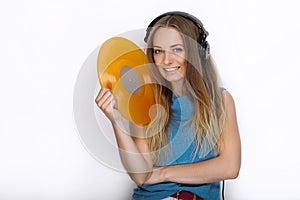 Happy young woman in big black professional dj headphones holding trendy yellow colorful vinyl record posing against white studio