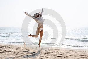 Happy young woman in bikini jumping on the beach