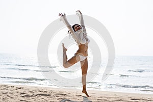 Happy young woman in bikini jumping on the beach