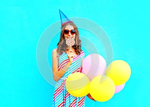 Happy young woman in a birthday cap with an air colorful balloons