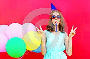 Happy young woman in a birthday cap near an air colorful balloons