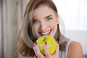 Happy young woman bitting green apple