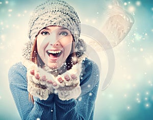 Happy young woman blowing snow