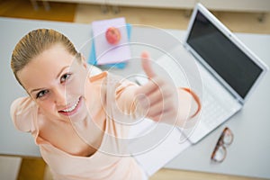 Happy young woman with books and laptop in kitchen