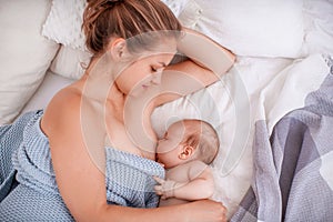 Happy young woman breastfeeding and hugging baby. Lactation newborn concept