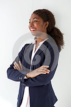 Happy young woman in business suit standing with her arms crossed and looking away