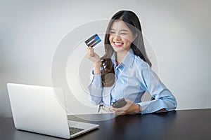 Happy young woman buying things online with copy space, using smartphone, laptop and credit card, enjoying shopping in internet