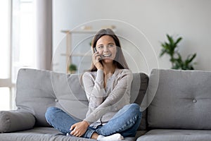 Happy young woman caller talking on the phone at home