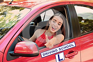 Happy young woman in car. Visiting driving school