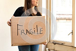 Happy young woman carrying a cardboard moving box for her new home, moving or new house concept