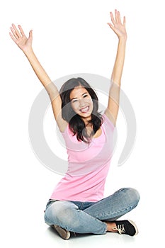 Happy young woman in casual wear sitting with raised arms smilin