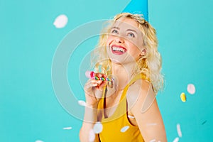 Happy young woman celebrating birthday party looking up at falling confetti