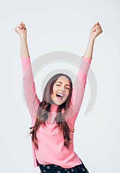 Happy young woman celebrating success with arms up isolated on white background