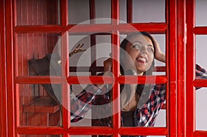 Happy young woman chatting on a public phone