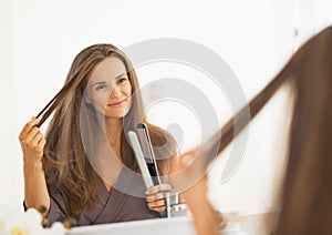 Happy young woman checking hair after straightening