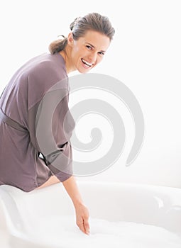 Šťastný mladá žena kontrola voda teplota v vana 