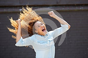 Happy young woman cheering with arms raised