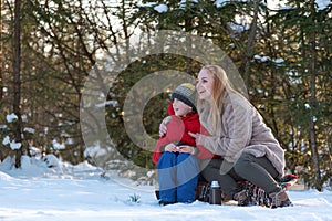 Happy young woman with child in winter forest on picnic. Mother and son outdoors. Winter time