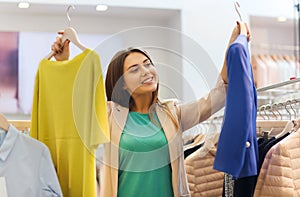 Happy young woman choosing clothes in mall