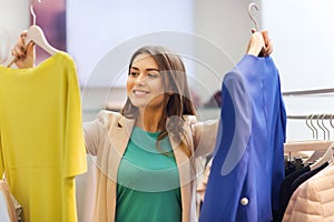 Happy young woman choosing clothes in mall