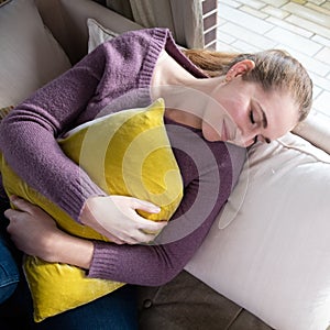 Happy young woman closing her eyes, holding a comfortable cushion