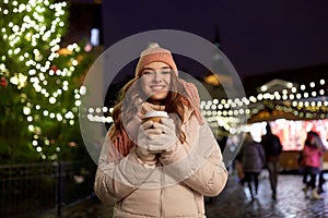 Happy young woman with coffee at christmas market