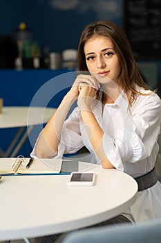 Happy young woman at coffee shop or cafe holding phone dreamy lady enjoying during work, looking at camera.