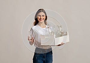 Happy Young Woman Collecting Garbage For Sorting, Holding Container With Glass Bottles