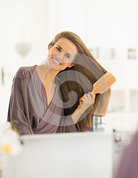 Contento giovane donna pettinatura capelli il bagno 