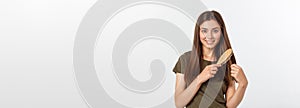 Happy young woman combing her long healthy hair on white background.