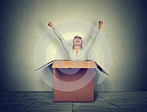 Happy young woman coming out from a small box