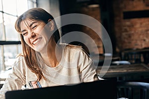 Happy young woman communicates online using computer