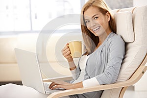 Happy young woman with computer and coffee mug
