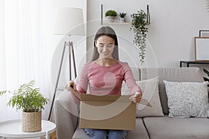 Happy young woman consumer opening package at home