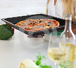 Happy young woman cooking pizza at home