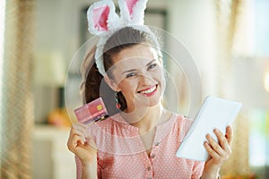 Happy young woman with credit card buying online on tablet PC