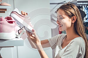 Happy young woman customer choosing pair of sneakers shoes