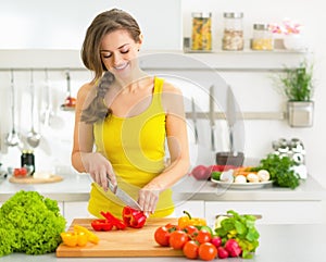 Happy young woman cutting fresh vegetables