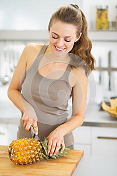 Happy young woman cutting pineapple