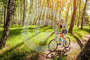 Happy young woman cyclist riding a mountain bicycle in spring forest