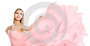 Happy Young Woman dancing with Chiffon Fabric waving on Wind. Smiling Blonde Model in Pink Summer Dress over White isolated