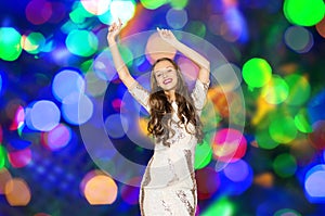 Happy young woman dancing over disco lights