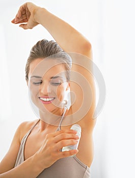 Happy young woman deodorant on underarm photo