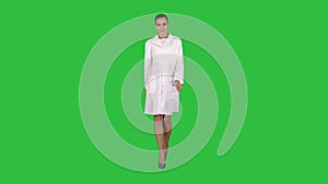 Happy young woman doctor dances on a green screen, chroma key.
