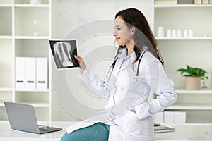 Happy young woman doctor looking at xray radiography image